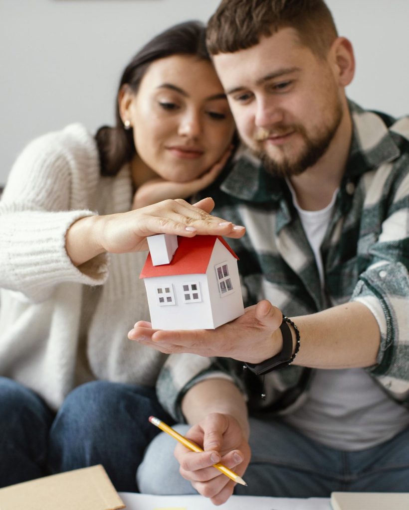 couple-holding-small-house-medium-shot